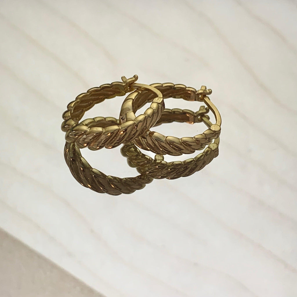 Gold hoop earrings on a light beige background
