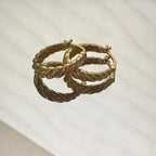 Gold hoop earrings on a light beige background